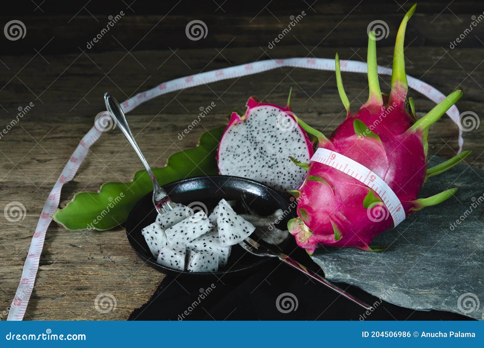 dragon fruit sliced Ã¢â¬â¹Ã¢â¬â¹in a dish the old wooden counterattack covered with black cloth and the fork is placed as an assembly,